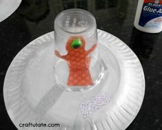 a paper plate with an orange plastic figure on it and glue around the base, sitting on a black table