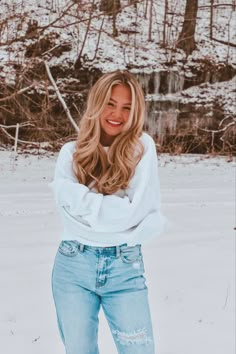 a woman standing in the snow with her hands on her hips and smiling at the camera