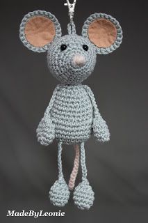 a crocheted mouse ornament hanging from a chain on a gray background