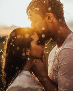 a man and woman kissing in front of snow falling from the sky with their noses close to each other