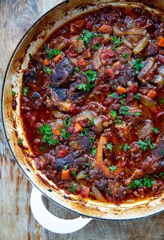 a pot filled with stew and vegetables on top of a wooden table next to the words, simple & easy osso buco