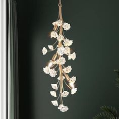 a chandelier hanging from the ceiling in a room with dark green walls and white flowers