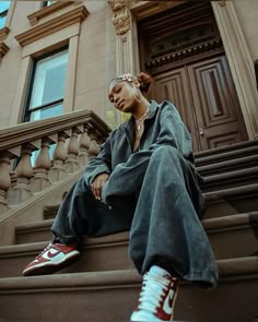 a woman sitting on the steps in front of a building with her feet propped up