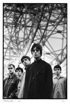 black and white photograph of young men standing in front of an electrical tower with one man looking at the camera