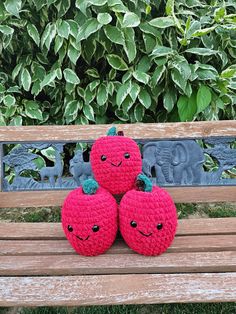 two crocheted apples sitting on top of a wooden bench next to each other