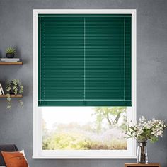 a living room with green blinds in the window and shelves on the wall behind it