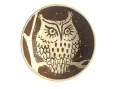 an owl is sitting on a tree branch in a round ceramic dish with black and white designs