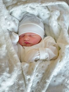 a newborn baby wrapped in a blanket and wearing a white knit hat is laying on it's side