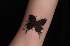 a black butterfly tattoo on the arm