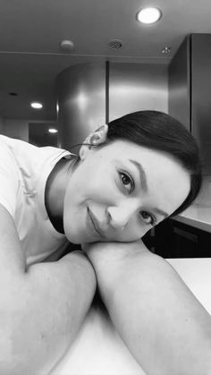 a black and white photo of a woman laying on a counter top in a kitchen