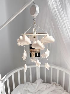 a baby crib with a mobile hanging from it's side and clouds on the ceiling