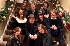 a group of people sitting on top of stairs in front of christmas decorations and garlands