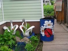 there are two metal birds sitting in the flower pots on the side of the house