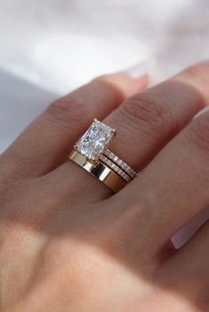 a woman's hand with two gold rings on it and a diamond ring in the middle