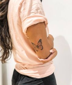 a woman with a butterfly tattoo on her left arm and right arm behind her back