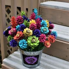 a bucket filled with colorful flowers sitting on top of a wooden bench