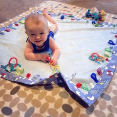 a baby laying on top of a blue and white blanket in the middle of a floor