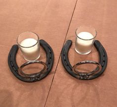 two glasses are sitting on the table with horseshoes around them and one is filled with milk