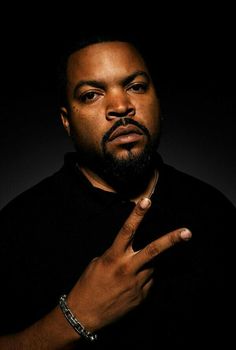 a man with a ring on his finger posing for the camera in front of a black background