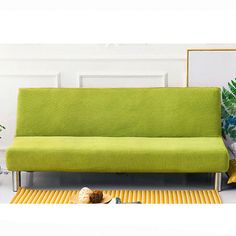 a green couch sitting on top of a yellow rug