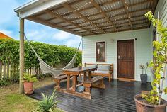 a wooden deck with a hammock and table on it in front of a house