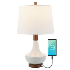 a phone plugged into a table lamp with a charger attached to the base