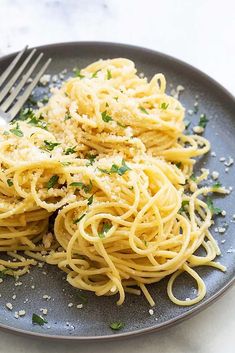 a plate of spaghetti with parmesan cheese on it and a fork next to it