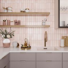 a kitchen with pink tiles and gold accessories on the countertop, along with shelves filled with dishes