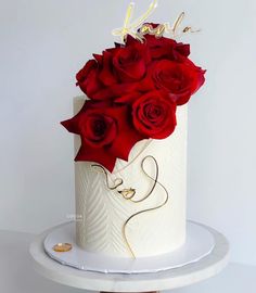 there is a white cake with red roses on the top and gold lettering that says love