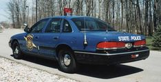 a state police car is parked on the side of the road in front of some trees