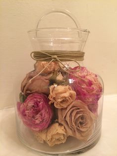 a glass jar filled with dried flowers on top of a white tablecloth covered table