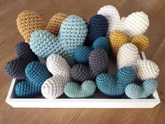 crocheted hearts are arranged on a white tray