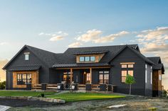 a black house with lots of windows on the front and side of it, surrounded by grass