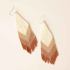 two pairs of beaded earrings with white and brown fringes on the end of them