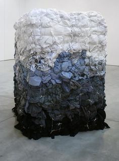 a large pile of cloth sitting on top of a cement floor next to a white wall