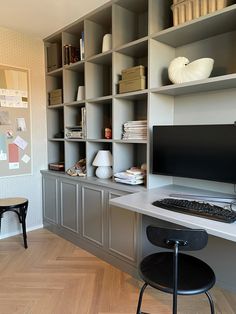 a desk with a computer on it in front of a book shelf filled with books