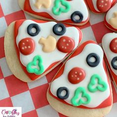 decorated cookies arranged in the shape of pizzas on a red and white checkered tablecloth