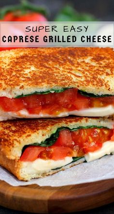 two grilled cheese sandwiches with tomatoes and spinach on top, sitting on a cutting board