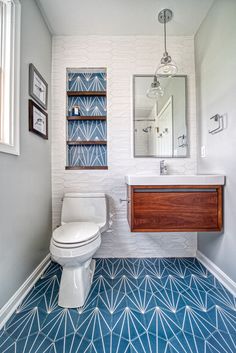 a white toilet sitting next to a sink in a bathroom under a mirror and a wooden cabinet