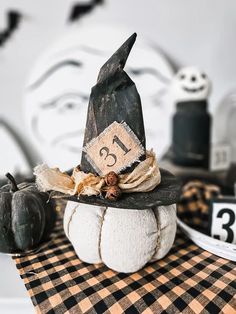 a black and white pumpkin with a witch's hat on it sitting on a checkered table cloth