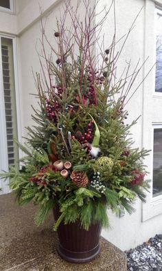 a potted plant with pine cones, berries and other plants in it sitting on a stone slab