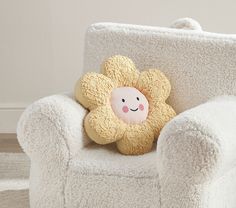 a stuffed animal sitting on top of a white chair next to a pillow with a smiling face