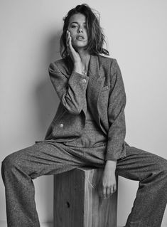 a woman sitting on top of a wooden box while talking on a cell phone and holding her hand to her face