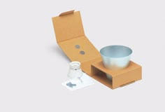 an open cardboard box with a cup and saucer in it on a white surface