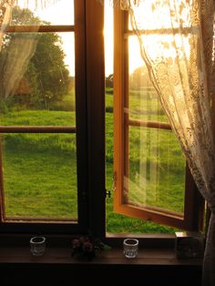 an open window with the sun shining through it and two cups in front of them