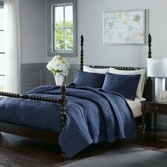 a bed with blue bedspread and white pillows