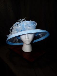 Sky Blue Symphony Derby Hat - Serene, Harmonious, Elegant This elegant derby hat is a perfect blend of femininity and sophistication. Its soft sky blue hue and intricate design create a captivating look. Sky Blue Color: A serene and calming color that adds a touch of elegance. Intricate Design: A beautiful, eye-catching piece with delicate details. Premium Materials: Crafted with high-quality materials for durability and comfort. Versatile Styling: Can be worn in various ways to suit your style. Make a Statement Today! Elevate your style with this unique accessory--shop now and turn heads at your next event! Adjustable Light Blue Fascinator For Royal Ascot, Blue Fedora For Summer Parties, Light Blue Summer Hats For Races, Light Blue Summer Hat For Races, Fitted Blue Brimmed Sun Hat, Blue Summer Fedora For Parties, Adjustable Light Blue Mini Hat For Kentucky Derby, Blue High Crown Hat With Adjustable Fit, Adjustable Brimmed Blue Top Hat