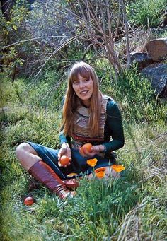 a woman sitting in the grass holding an orange