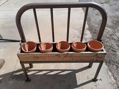 a bench with four clay pots on it and a bike parked in the back ground