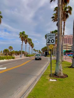 a speed limit sign on the side of a road with palm trees in the background